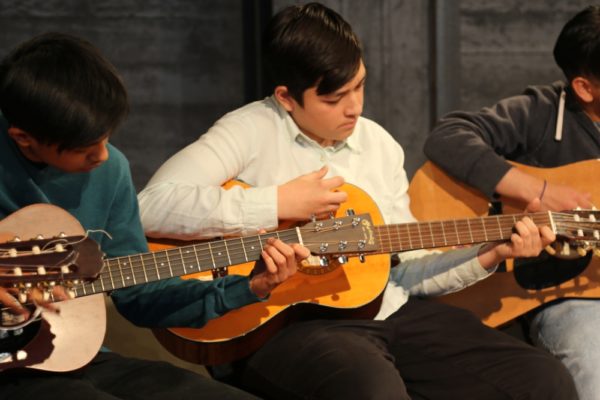 3 teenage kids playing guitar