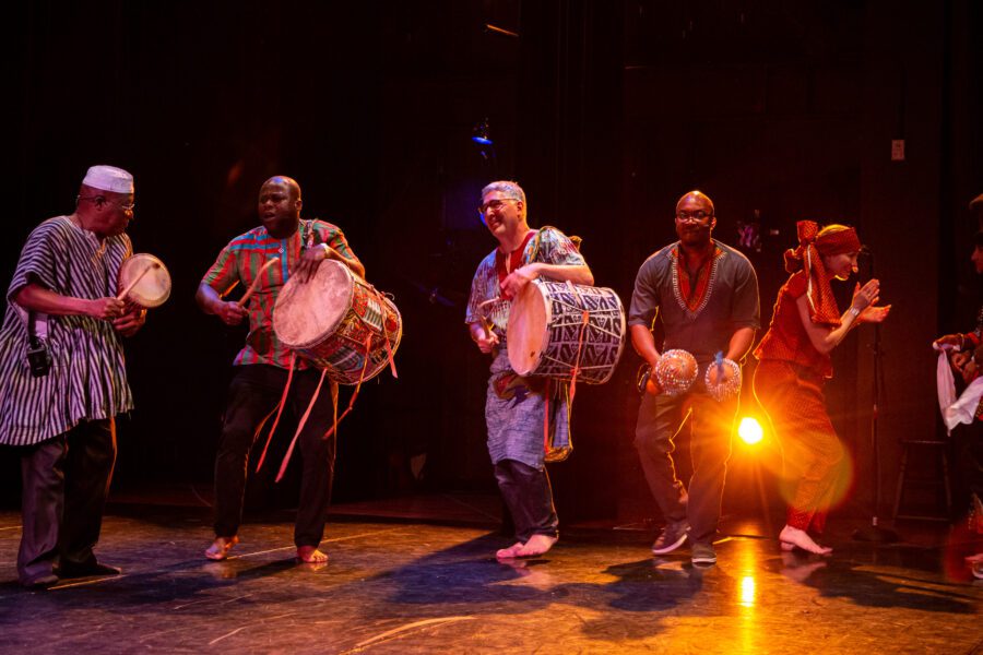 Four west African Drummers and two dancers, back-lit